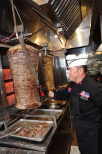 Chef slicing meat in kitchen at donerg