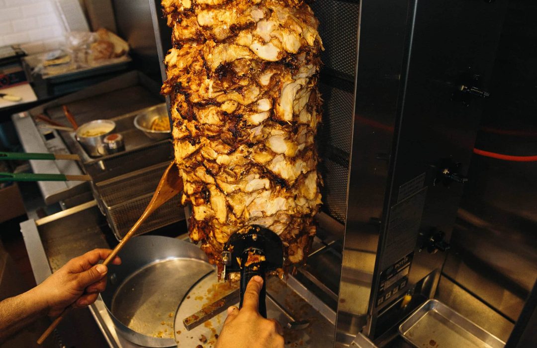 Authentic chicken döner cooking on a vertical rotisserie at DonerG Mediterranean Grill.