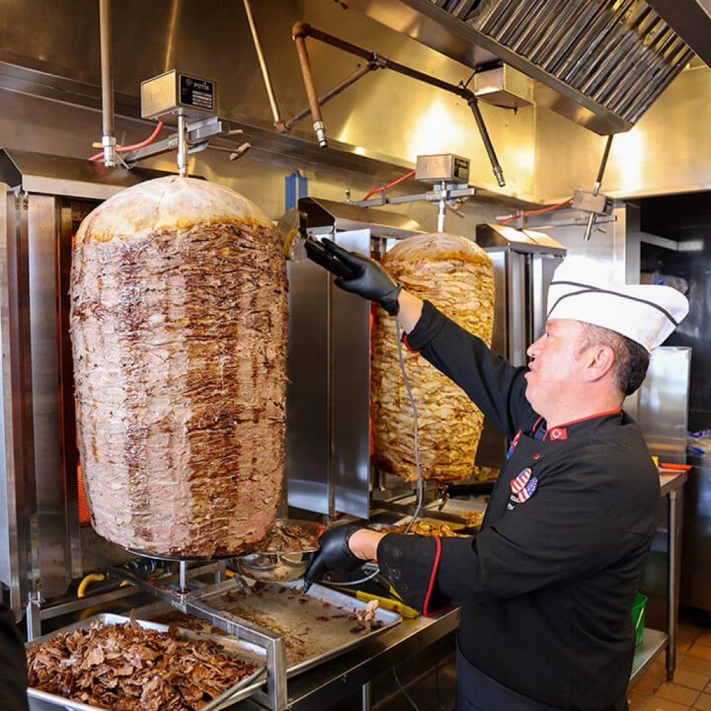 Chef slicing meat from donerg's vertical rotisserie.