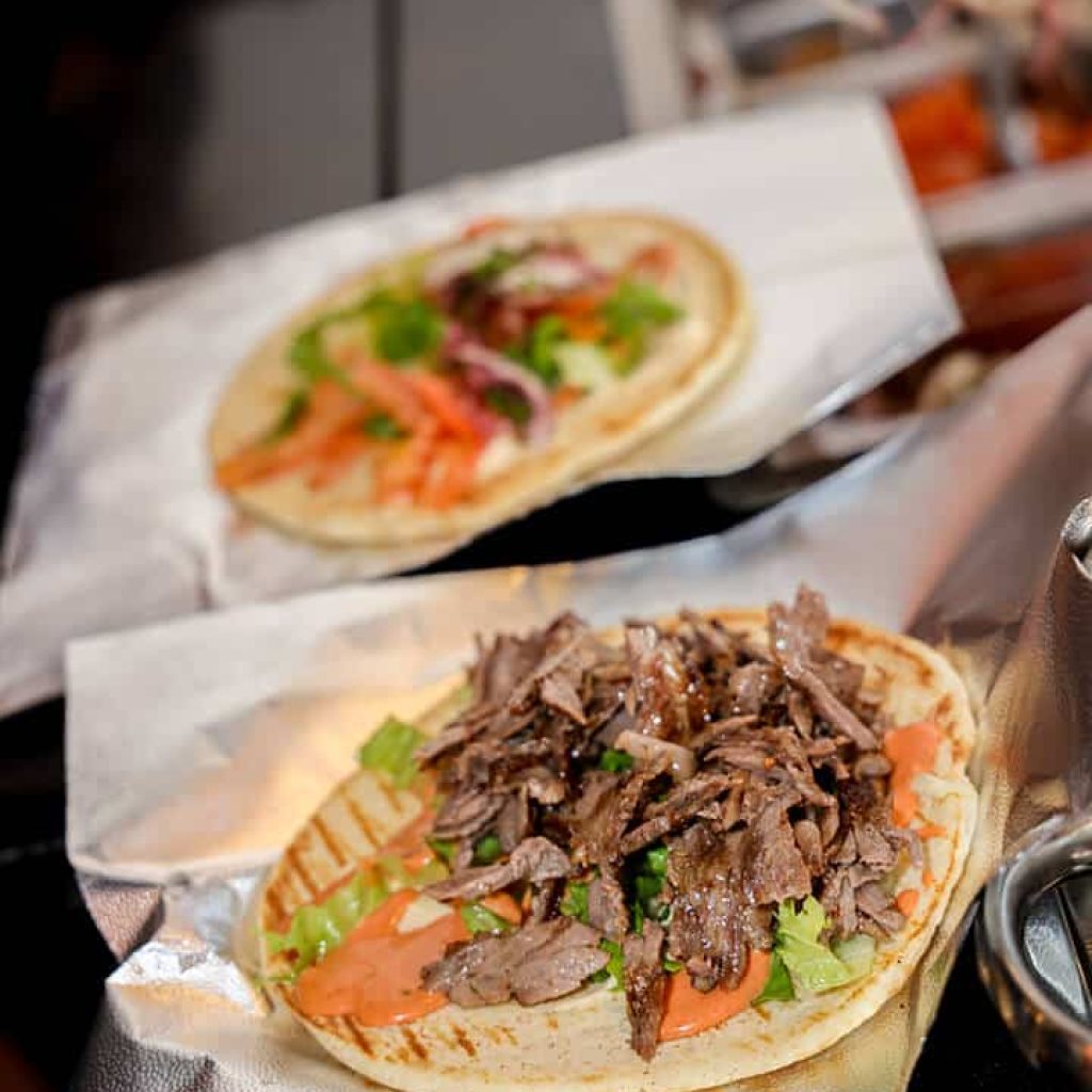 donerg pita sandwich being prepared with meat and toppings