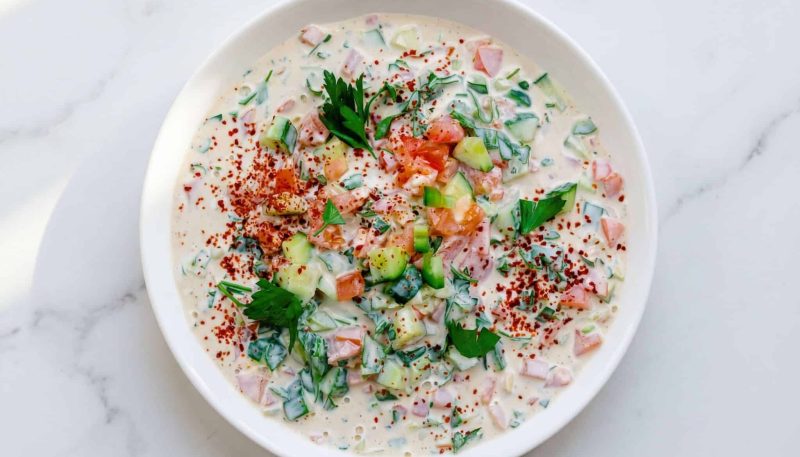 cucumber tomato tahini salad with fresh herbs and creamy dressing in a bowl