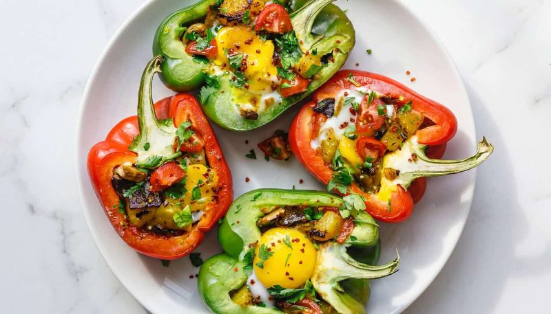 breakfast stuffed bell peppers with eggs, vegetables, and herbs on a plate