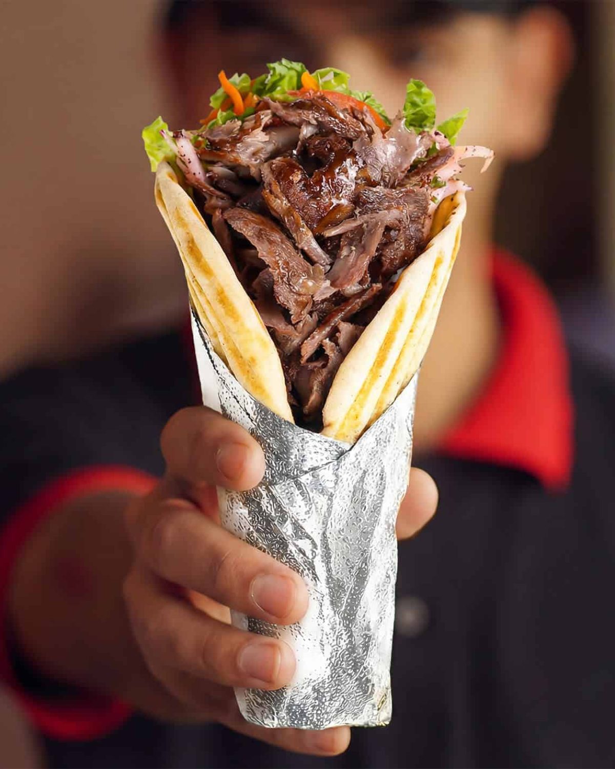 Döner pita sandwich with grilled pita, hummus, and fresh vegetables