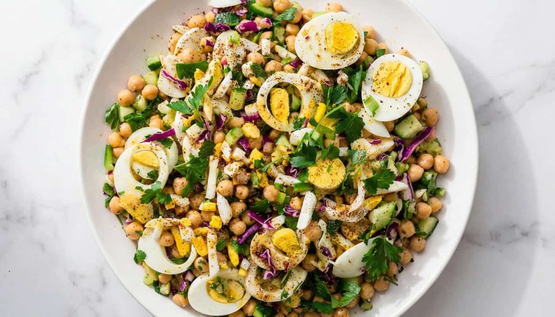 Mediterranean chickpea egg salad with herbs, cucumbers, and sliced boiled eggs
